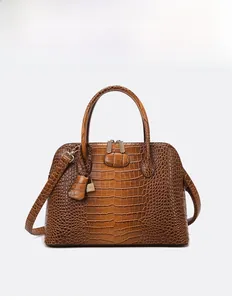 Detail of brown crocodile pattern leather handbag with metal padlock and top handle