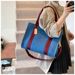 Détail du sac cabas en denim bleu avec lanières brun rouge et garnitures dorées