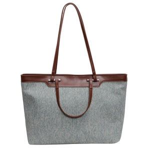 Large blue canvas tote bag with brown leather trim and dual handles on white background