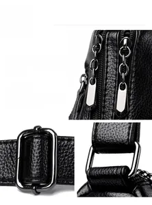 Close-up of black lychee grain leather crossbody bag with dual zippers and silver hardware
