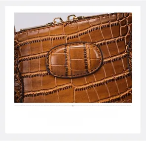 Detail of brown crocodile pattern leather bag featuring a gold metal zipper closure