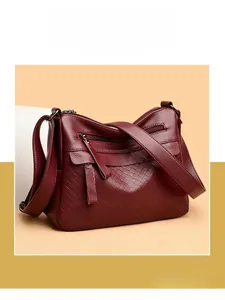 Detailed macro shot of burgundy lychee grain leather handbag and metallic hardware