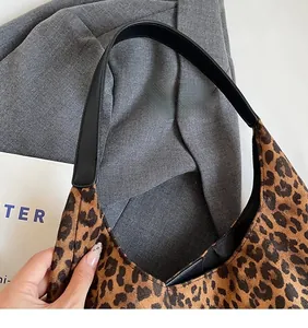 Detail of leopard print shoulder bag with smooth black synthetic leather long strap