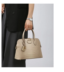 Detail of beige faux crocodile texture and gold hardware on a stylish handbag