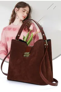 Detail of dark brown suede tote bag with golden buckle and sleek leather shoulder strap