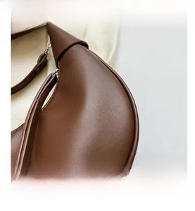 Detailansicht der braunen halbmondförmigen Handtasche mit Lederstruktur und feinen Nähten