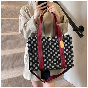 Détail du sac cabas en tweed à carreaux avec franges, anses rouges et fermoir fleuri jaune