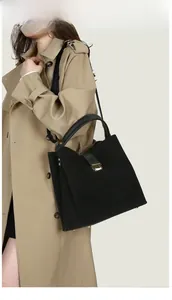 Woman in trench coat wearing black matte bucket bag with gold buckle as a shoulder bag