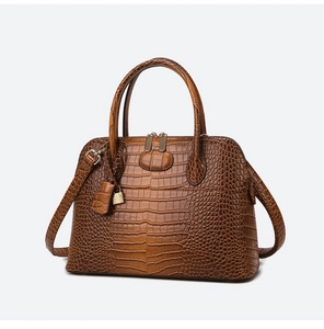 Macro detail of brown crocodile embossed leather bag with gold hardware and logo padlock