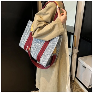 Détail du sac cabas bleu texturé avec bandoulière rouge-brun et poignée en cuir jaune