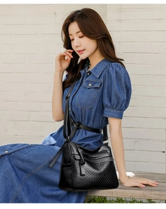 Detail of high-quality black quilted crossbody bag with adjustable strap on a female model
