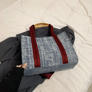 Détail du cabas tissé bleu et blanc avec sangle rayée rouge et poignée en bois
