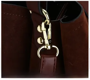 Detail of premium gold metal hook and dark brown suede patchwork texture on handbag