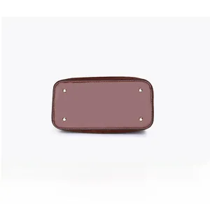 Detailed bottom view of brown leather bag featuring four protective gold metal feet