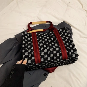 Détail du cabas en toile à carreaux avec sangle rouge et poignée en cuir marron