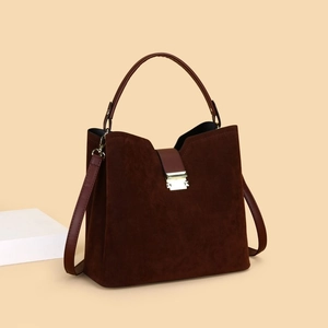Detail view of deep brown matte leather handbag with gold square buckle and V-cut design