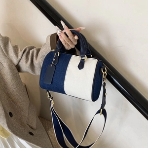 Grand sac cylindre en jean contrasté avec bandoulière large bleue et anses en cuir