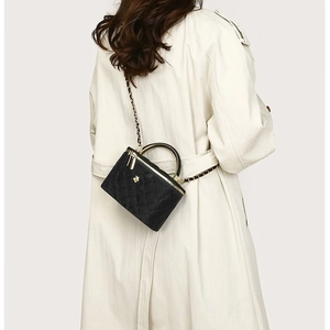 Quilted black mini handbag with gold bee emblem shown on a beige trench coat