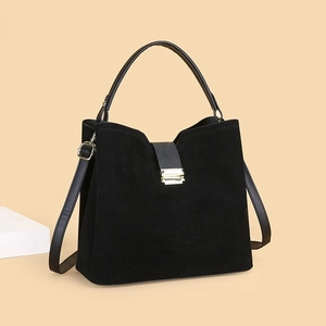 Detailed view of black suede bucket bag with gold lock and premium smooth leather straps