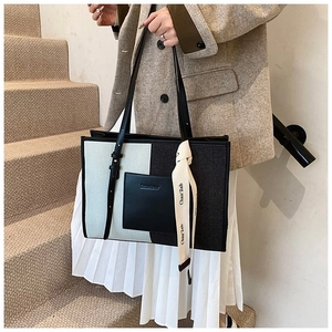 Detail of a large canvas tote bag with contrast stitching and leather pocket design
