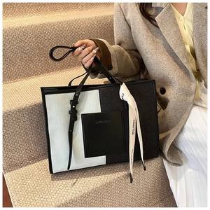 Detail of canvas tote bag featuring color-block design and decorative silk ribbon