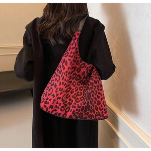 Detailed view of leopard print tote bag with black straps worn on woman shoulder