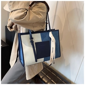 Detail of color-block canvas tote bag with contrast pocket and branded silk scarf detail