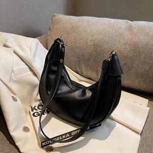 Detail einer schwarzen Hobo-Tasche mit verstellbarem Riemen auf hellem Blazer