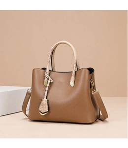 Close-up of brown pebbled leather handbag with contrasting beige crocodile pattern handles