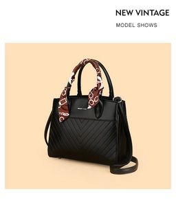 Detail of black V-quilted tote bag featuring a decorative silk scarf wrapped on handle