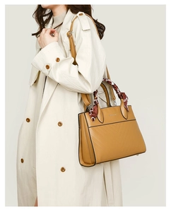Detail of camel tote bag with V-quilted texture and stylish silk scarf on the handle