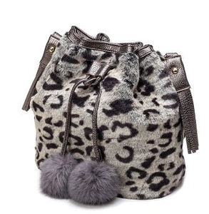 Detail of leopard print faux fur bucket bag featuring plush pom-poms and drawstring closure