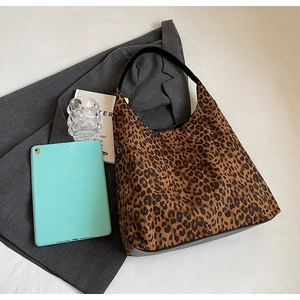 Detailed view of leopard print hobo handbag on desk with grey blazer and tablet