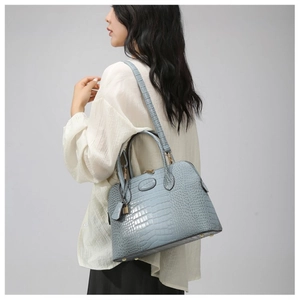 Detail of light blue croc-embossed handbag showing smooth texture and metal bottom feet