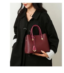 Detailed shot of wine red litchi leather tote bag with metallic buckle and round handles