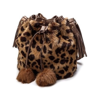 Detail of leopard print faux fur bucket bag with tassels and decorative plush pom-poms