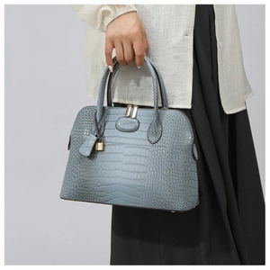 Detail of light blue croc-embossed handbag with gold padlock and sturdy twin handles