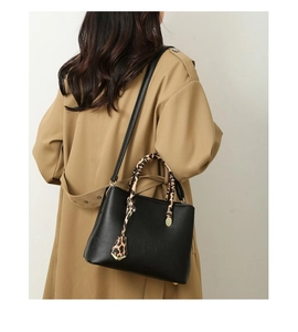 Detail of black pebbled leather tote featuring leopard print scarf handle and gold hardware