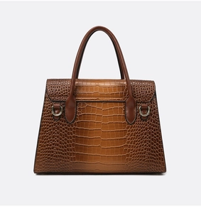 Detail of brown crocodile pattern leather handbag featuring classic flap and metal D-rings