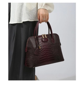 Close-up of deep burgundy faux crocodile embossed texture on a women's handbag with metal zipper