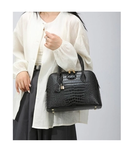 Detail of black crocodile pattern leather bag with gold buckle and bottom metal studs