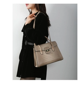 Close-up of khaki crocodile pattern handbag featuring a metal turn-lock and handles