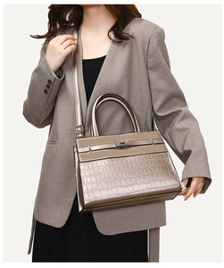 Macro view of champagne gold faux crocodile texture and metallic twist-lock on handbag