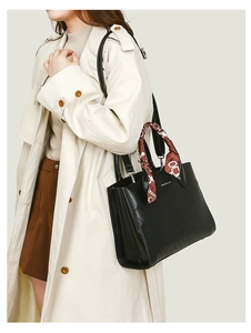 Close-up of quilted black leather tote bag with decorative silk scarf on handle
