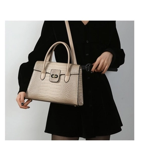 Detailed view of crocodile pattern texture and metal twist lock on the brown tote bag