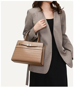 Close-up of brown crocodile embossed leather handbag with vintage gold metal twist lock