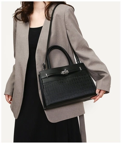 Close-up of black crocodile-embossed leather handbag with silver metallic twist lock