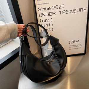 Schicke schwarze Halbmond-Hobo-Tasche mit Ösenriemen auf einem minimalistischen Tisch