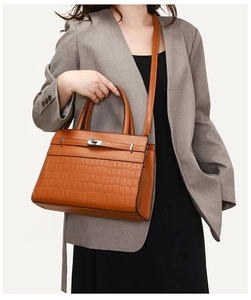 Detail of brown embossed leather handbag showing metal turn-lock and crocodile texture