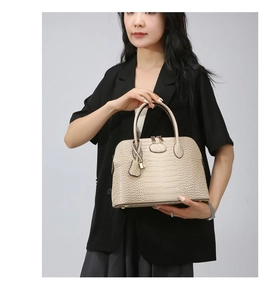 Detail of light beige crocodile pattern handbag with elegant stitching and metal padlock